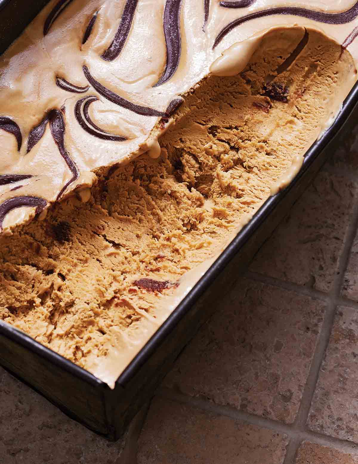 A metal loaf pan filled with no-churn coffee ice cream with a long scoop of ice cream missing.