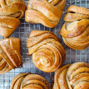 Several Swedish cardamom buns cooling on a wire rack.
