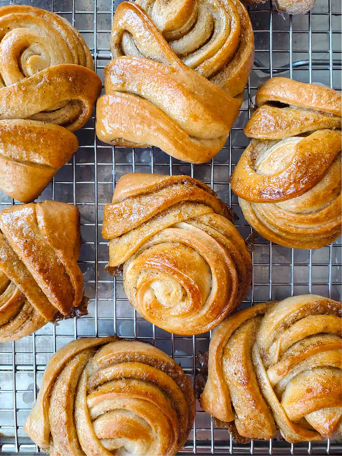 Several Swedish cardamom buns cooling on a wire rack.