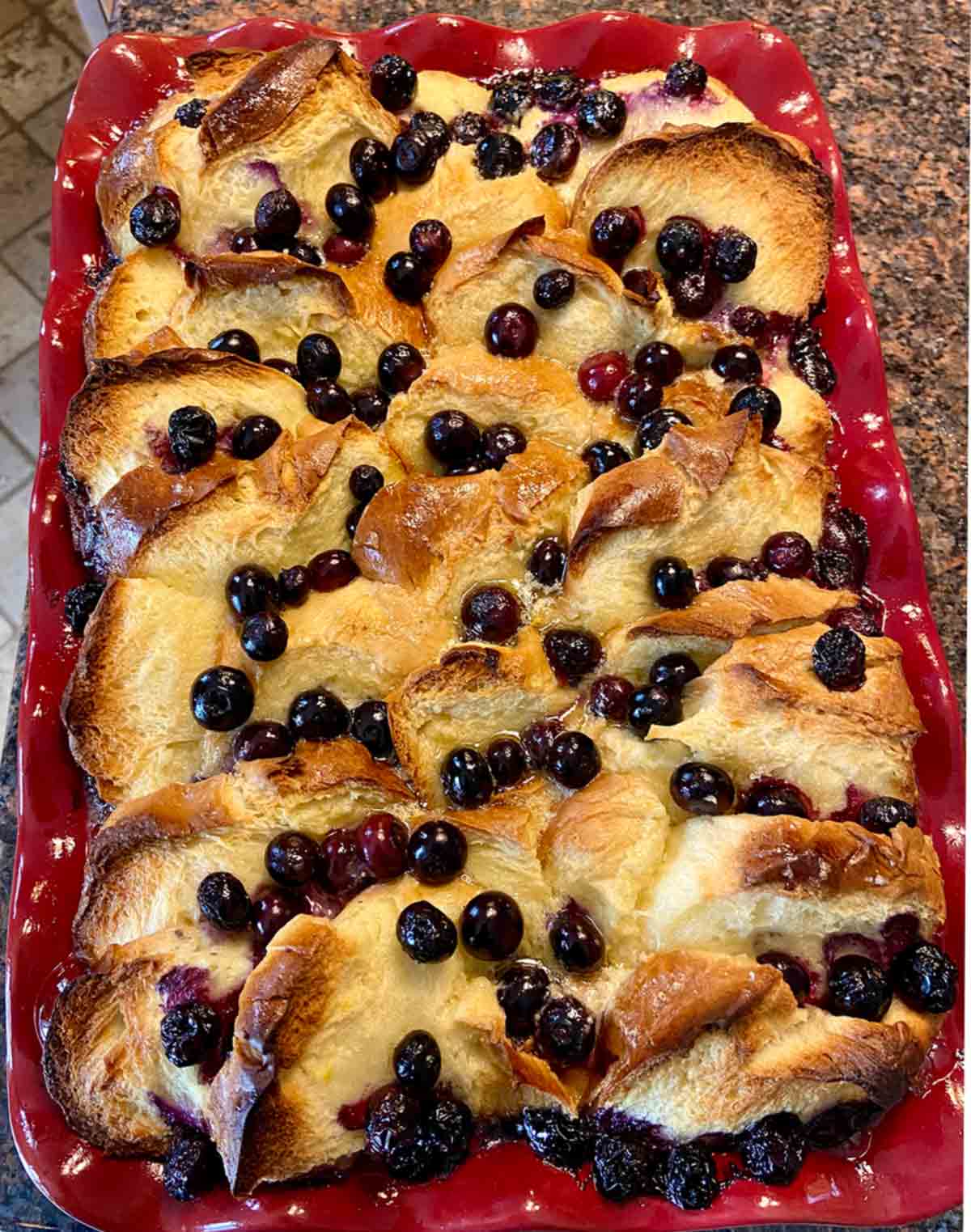 A red baking dish filled with blueberry brioche French toast casserole.