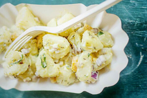 A cardboard bowl filled with easy potato salad an a plastic fork resting on top.