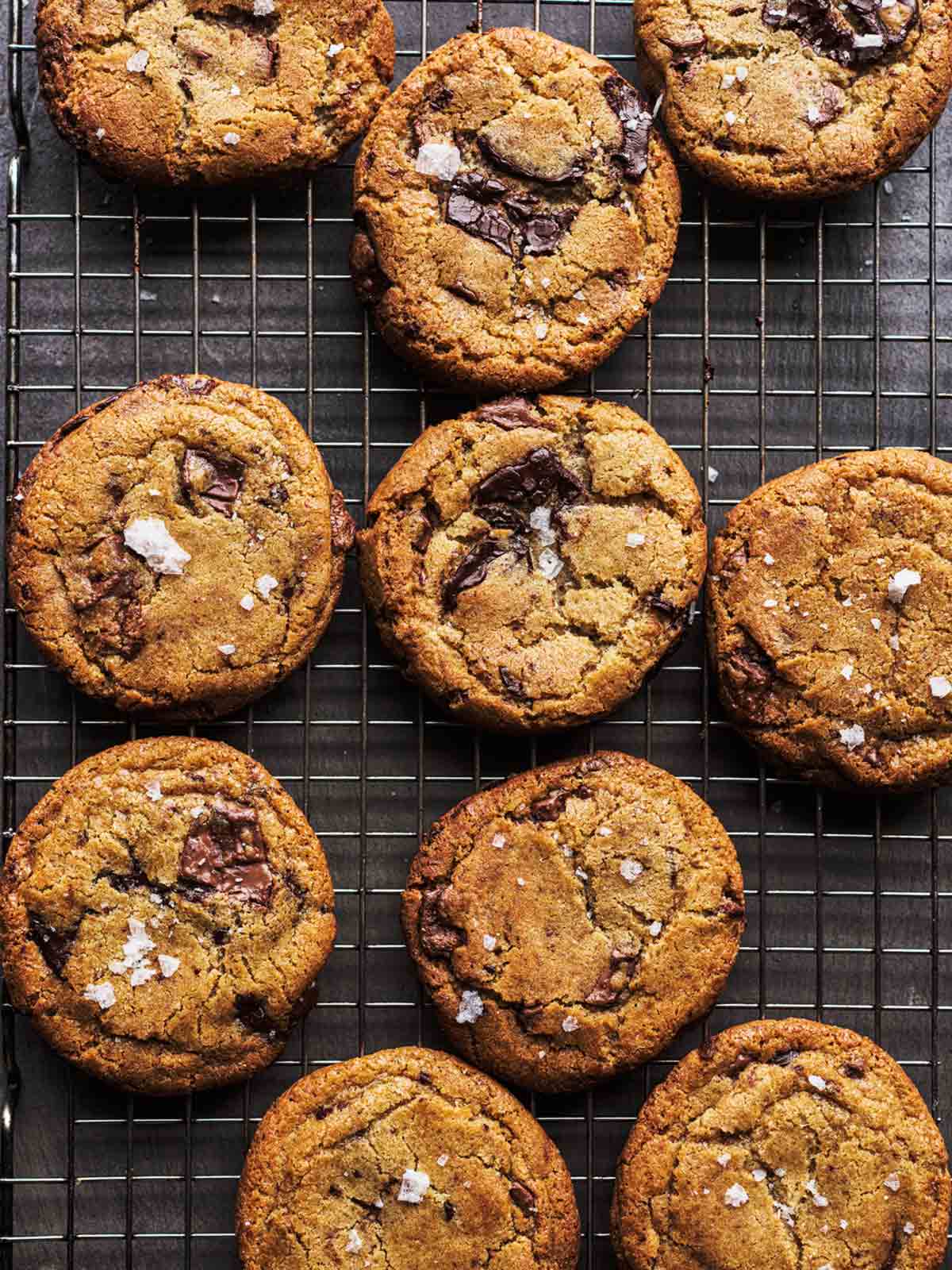 Ten salted brown butter chocolate chunk cookies on a wire cooling rack.