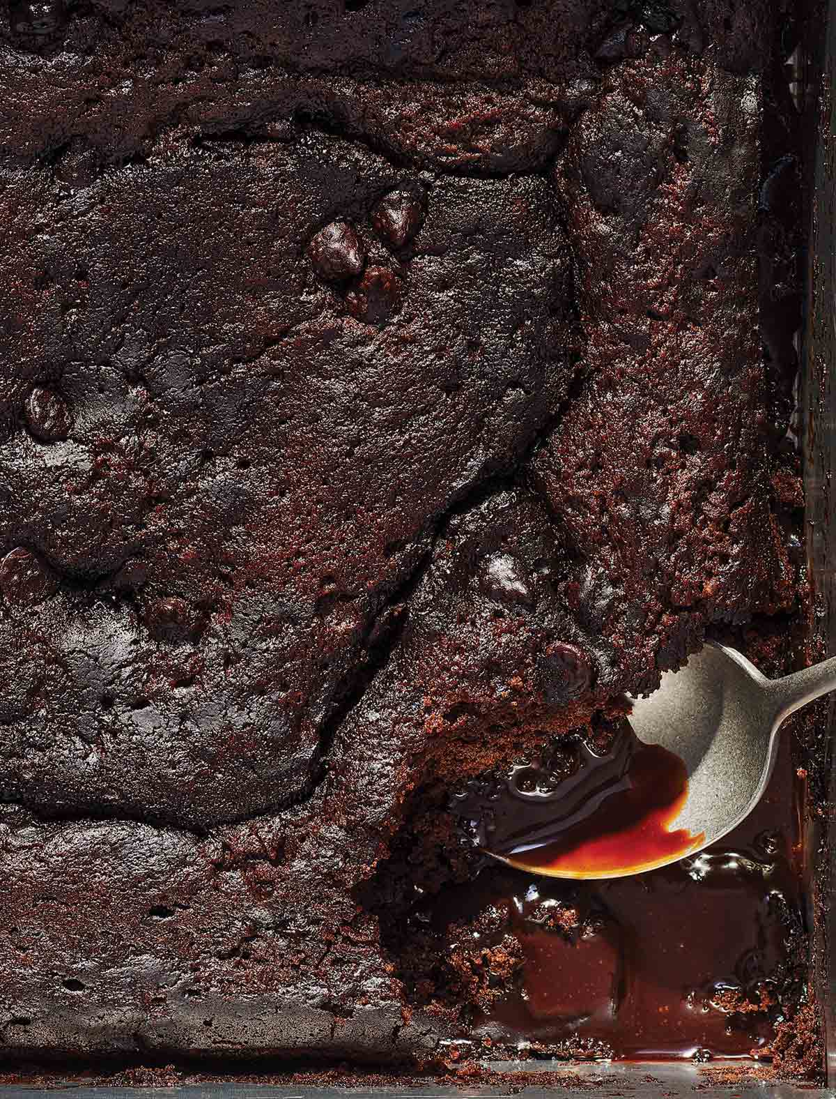 A baking dish filled with spicy hot fudge pudding cake and a spoon scooping out a portion.