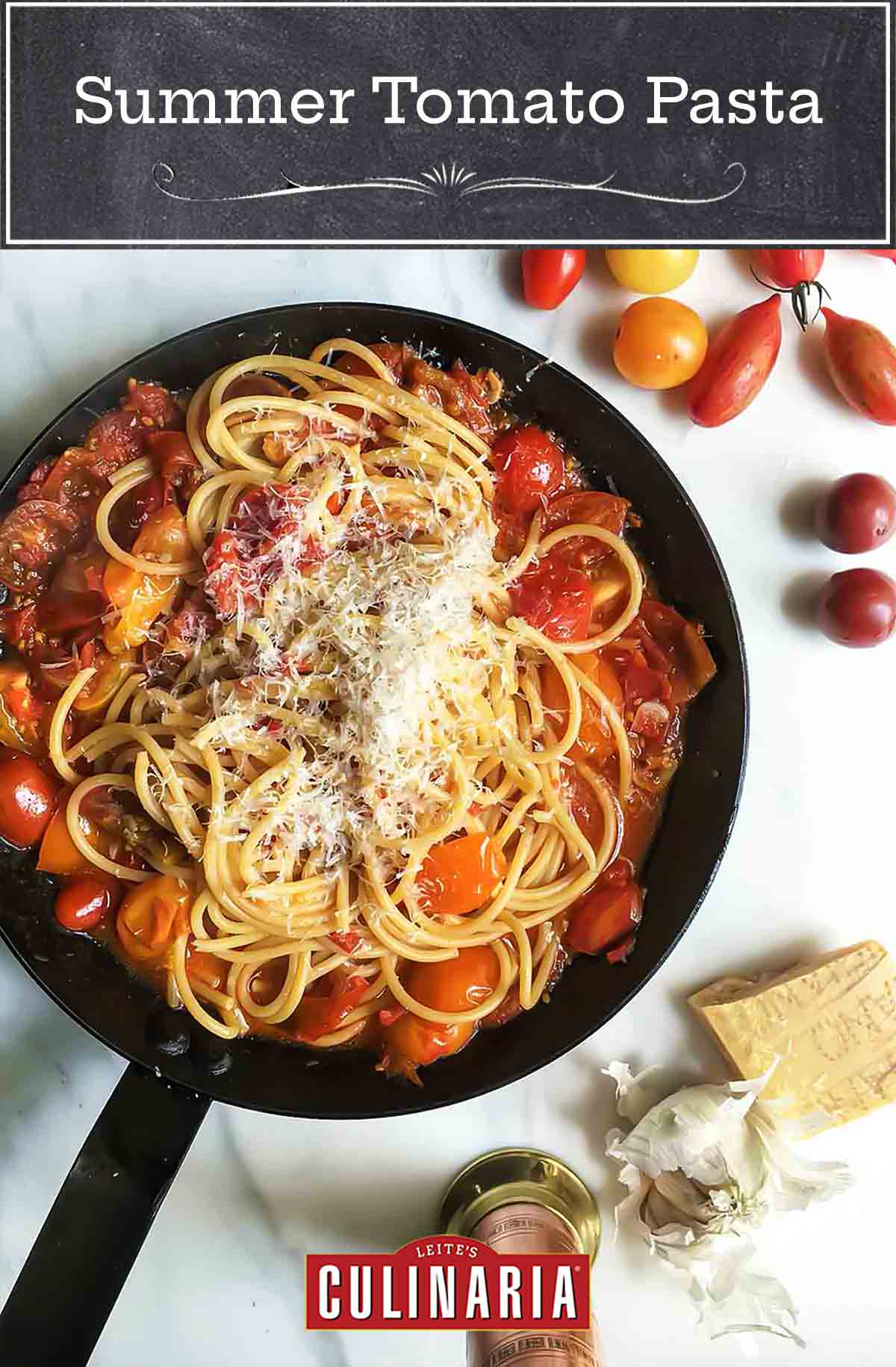 A black skillet filled with summer tomato pasta, sprinkled with fresh Parmesan cheese.