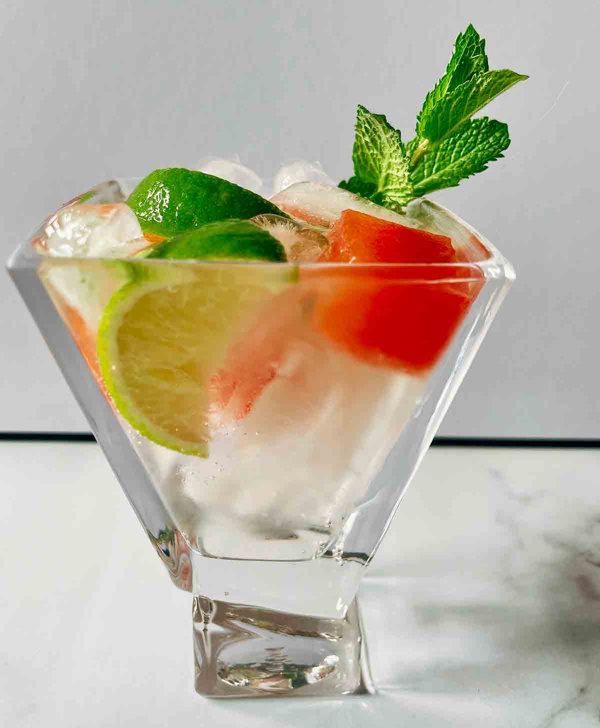 A short highball glass filled with watermelon Moscow mule, garnished with a mint sprig.