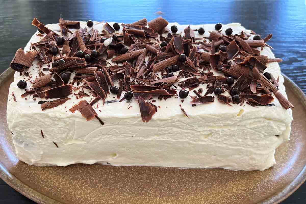 A whole icebox cake with condensed milk whipped cream with chocolate shavings on top.
