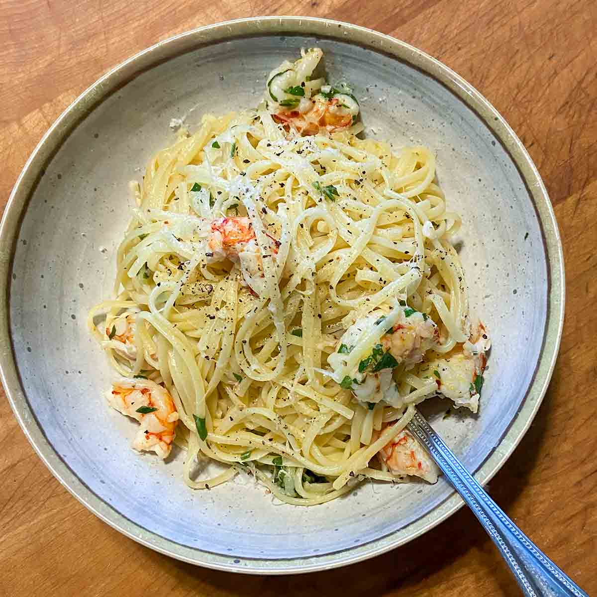 A pasta bowl filled with lemon garlic shrimp pasta an a fork resting inside the pasta.