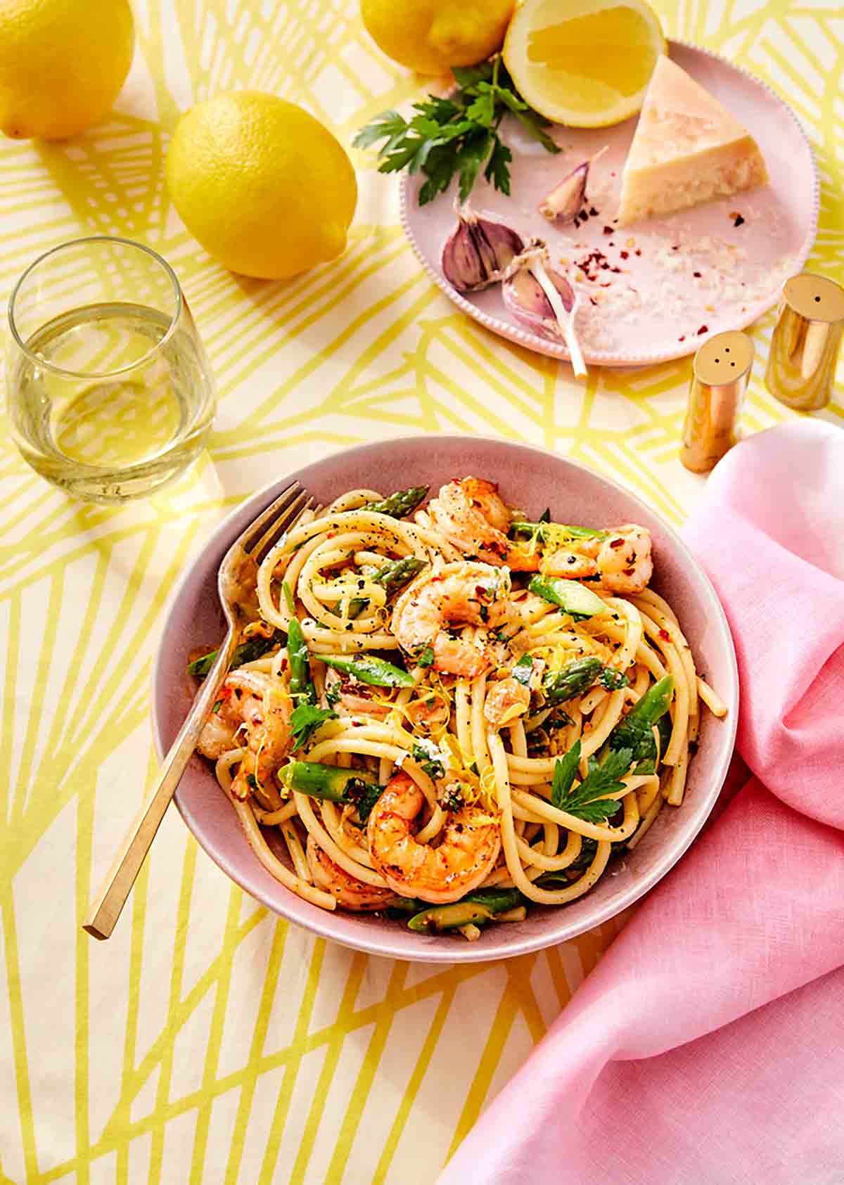 A pink bowl filled with lemon garlic shrimp pasta with a fork resting inside.