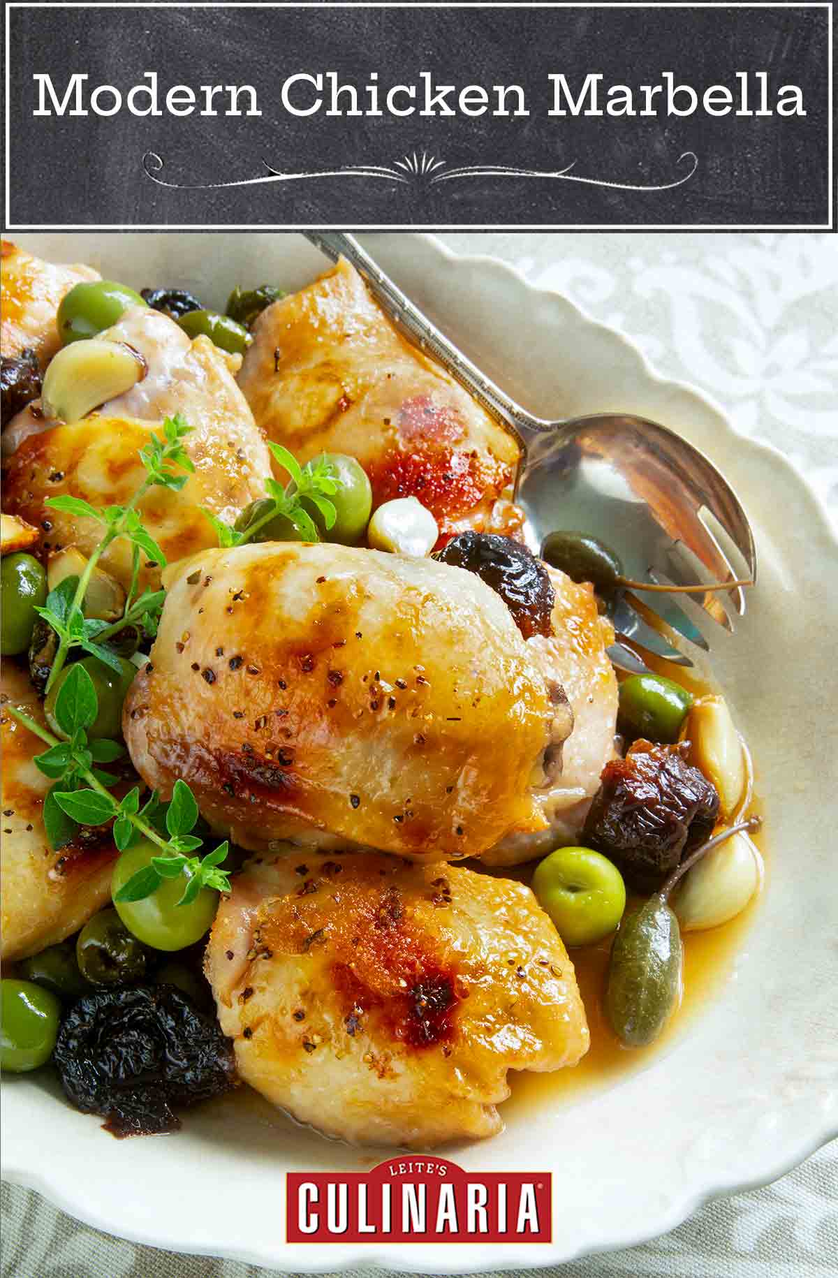 Pieces of chicken Marbella in a white serving dish with prunes, olives, and capers, garnished with fresh thyme and a serving spoon on the side.