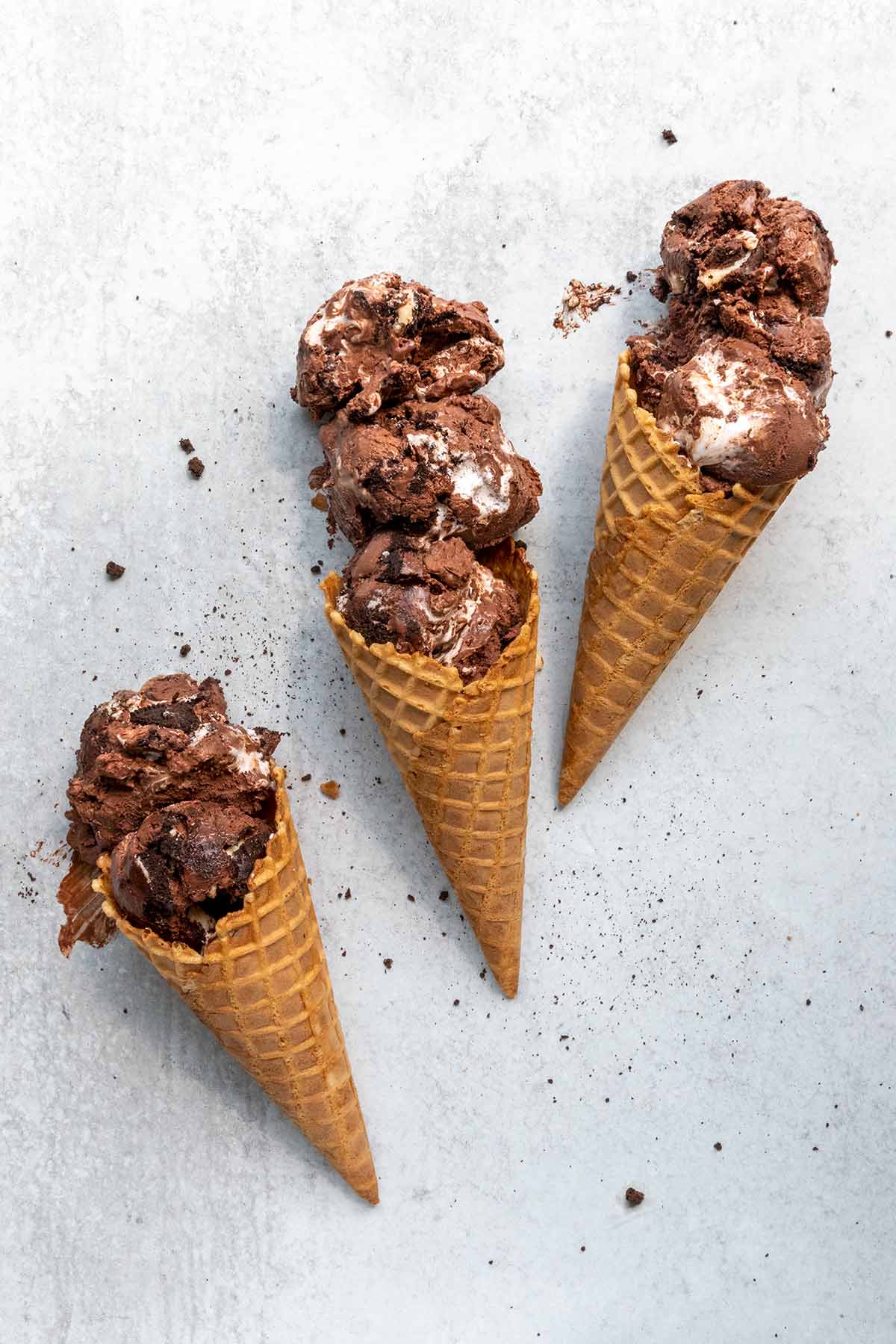 Three waffle cones, each filled with two or three scoops of chocolate Oreo ice cream.