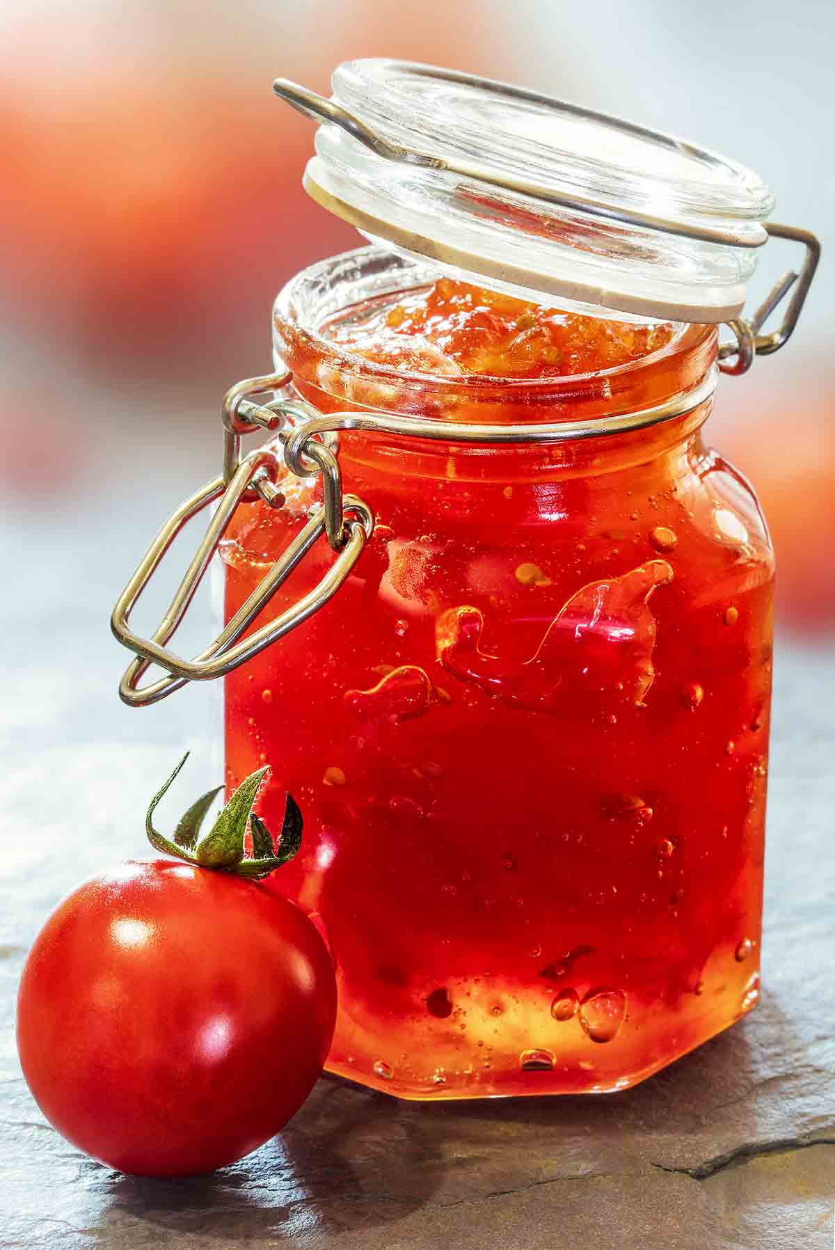 A jar of Portuguese tomato jelly with a small tomato next to it.