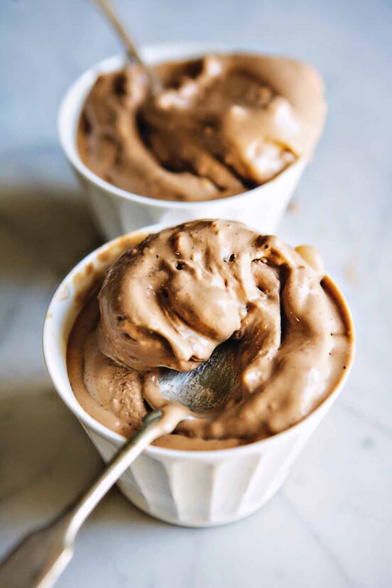 Two cups with scoops of chocolate hazelnut gelato, known as gelato di gianduia, with a spoon.