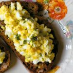 An open face egg salad sandwich on toasted whole wheat.