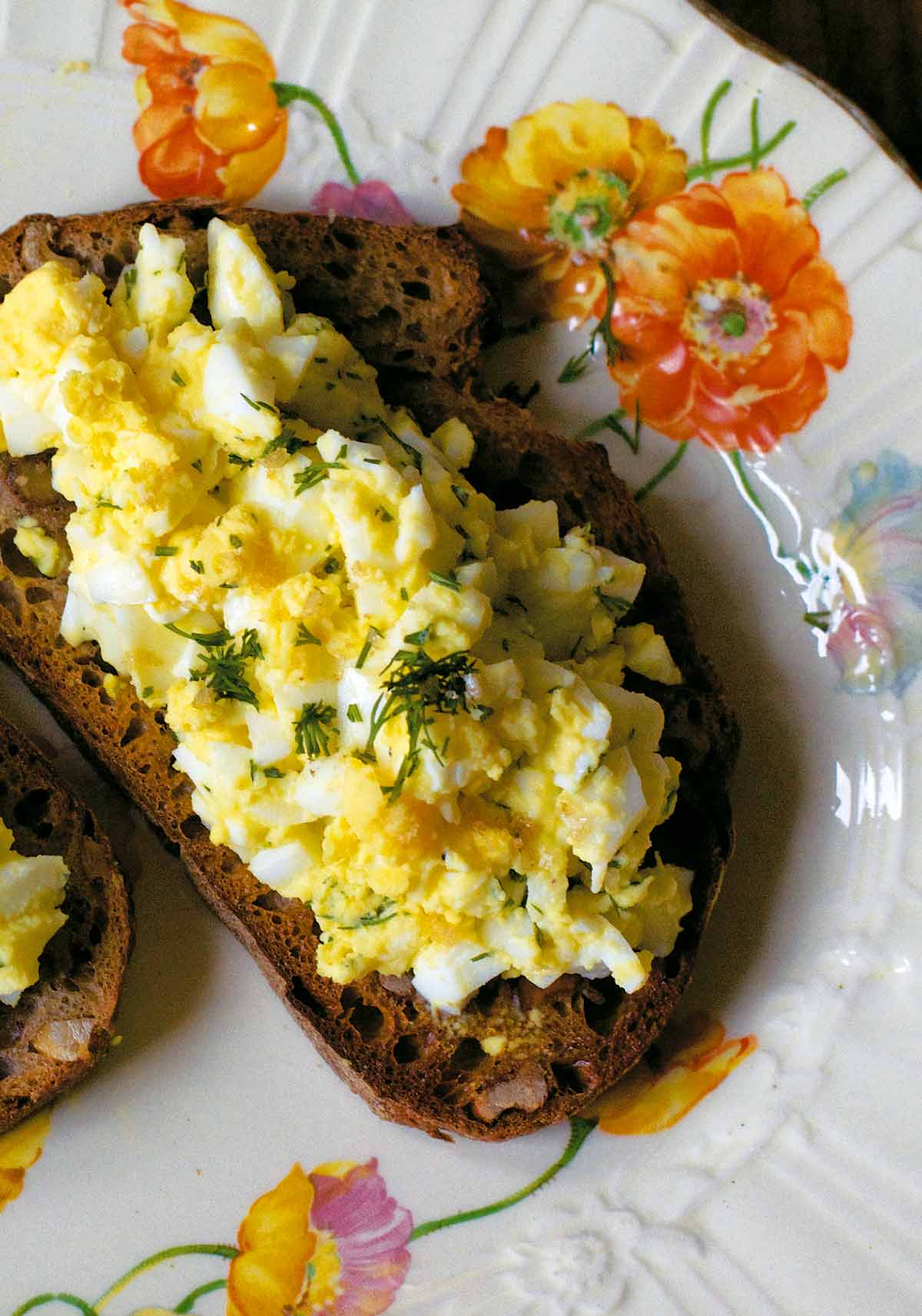 An open face egg salad sandwich on toasted whole wheat.