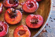 An oval dish filled with roasted plums, topped with star anise.