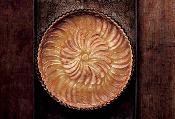 A round tart filled with cooked sliced apples in a concentric pattern.