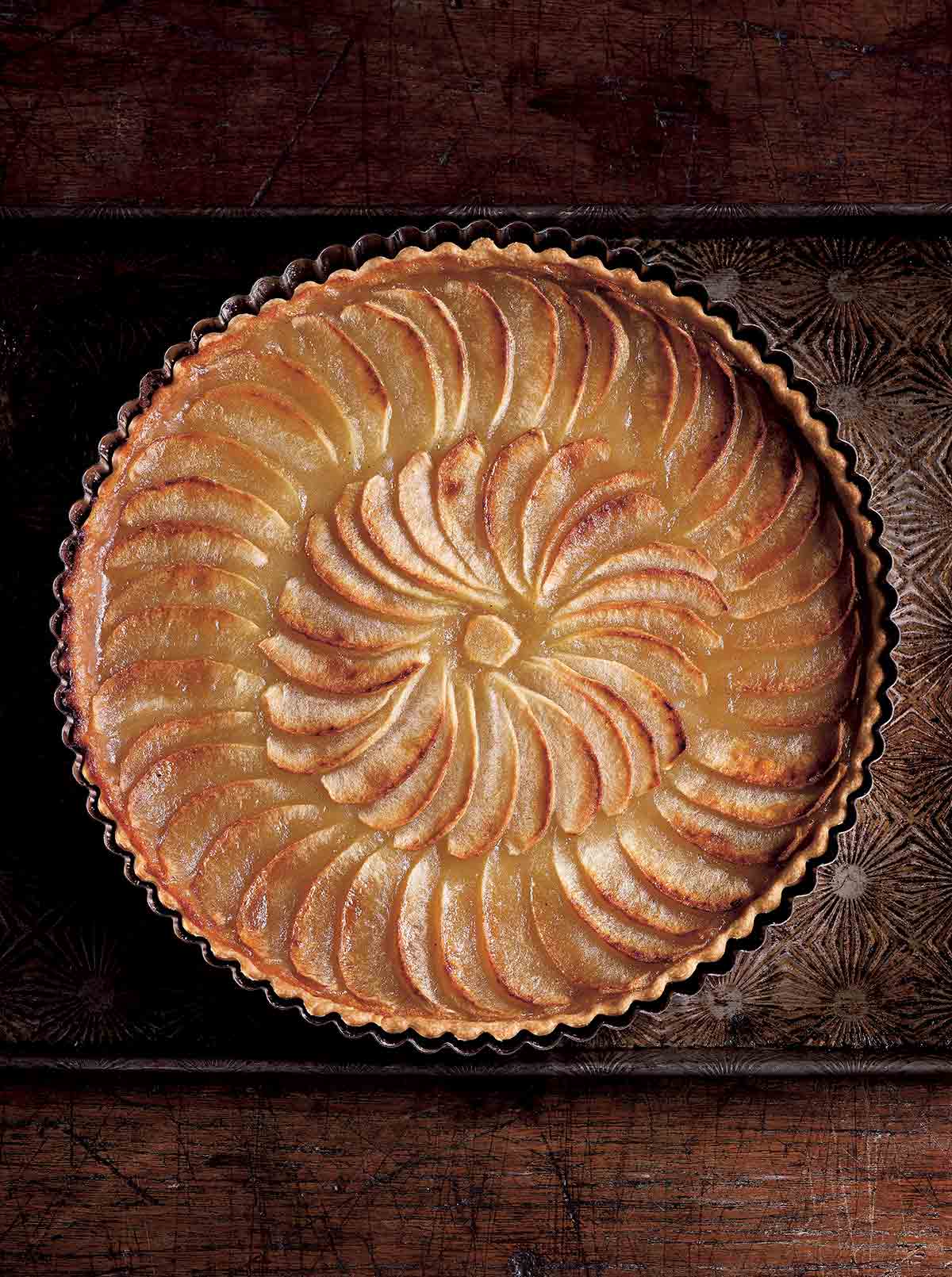 A round tart filled with cooked sliced apples in a concentric pattern.