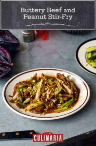A white and brown plate filled with beef and leek stir fry, topped with peanuts.