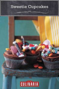Several chocolate cupcakes with chocolate frosting and candies on top on a wooden chair.