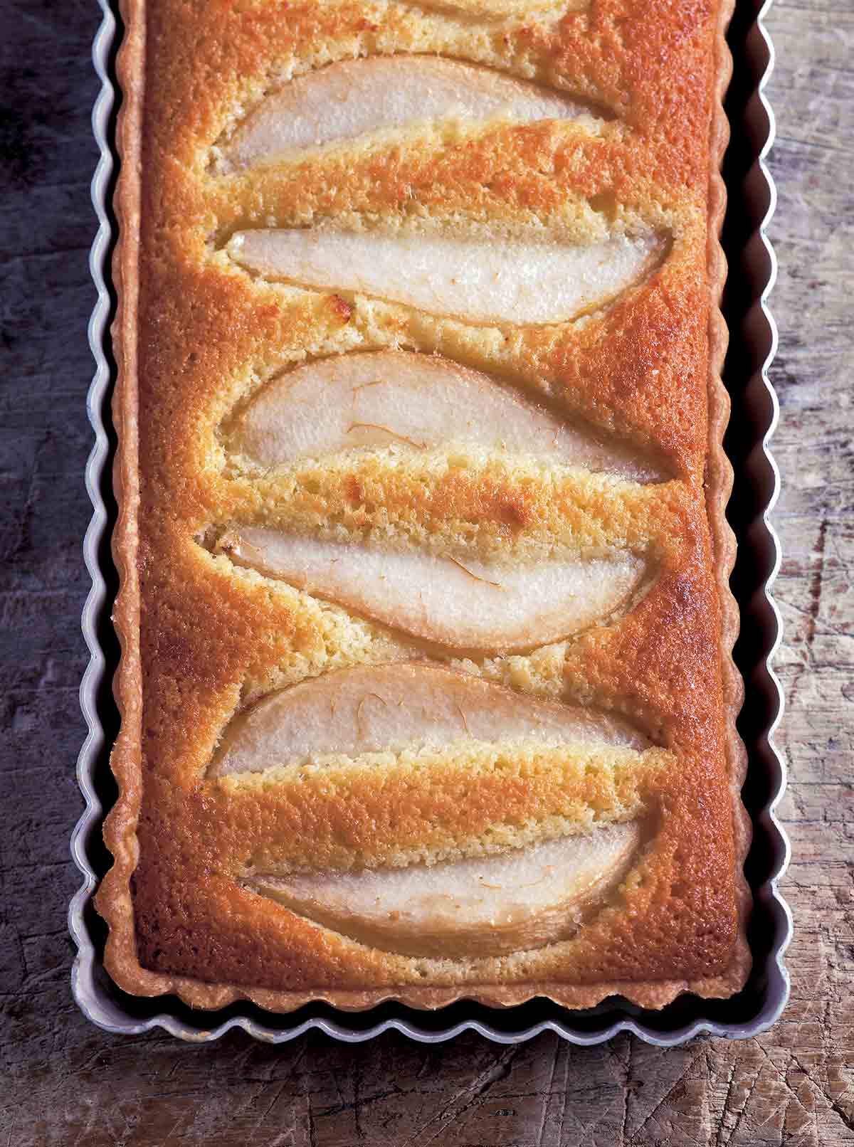 A rectangular tart with wedges of pear baked into it in a rectangular tart pan.