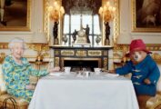 Queen Elizabeth II and Paddington Bear sitting at a table for tea.
