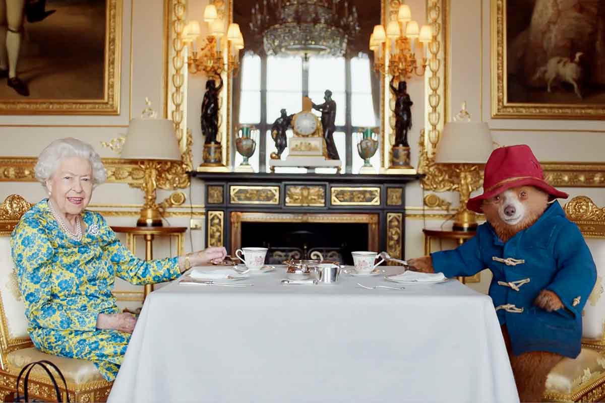 Queen Elizabeth II and Paddington Bear sitting at a table for tea.