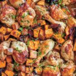 A sheet pan filled with roast chicken pieces, sweet potato chunks, dates, and a parsley garnish.
