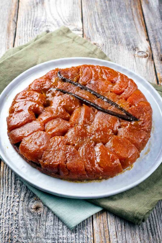 A tarte tatin on a white plate on a wooden table.