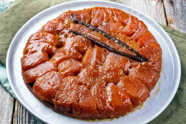 A tarte tatin on a white plate on a wooden table.
