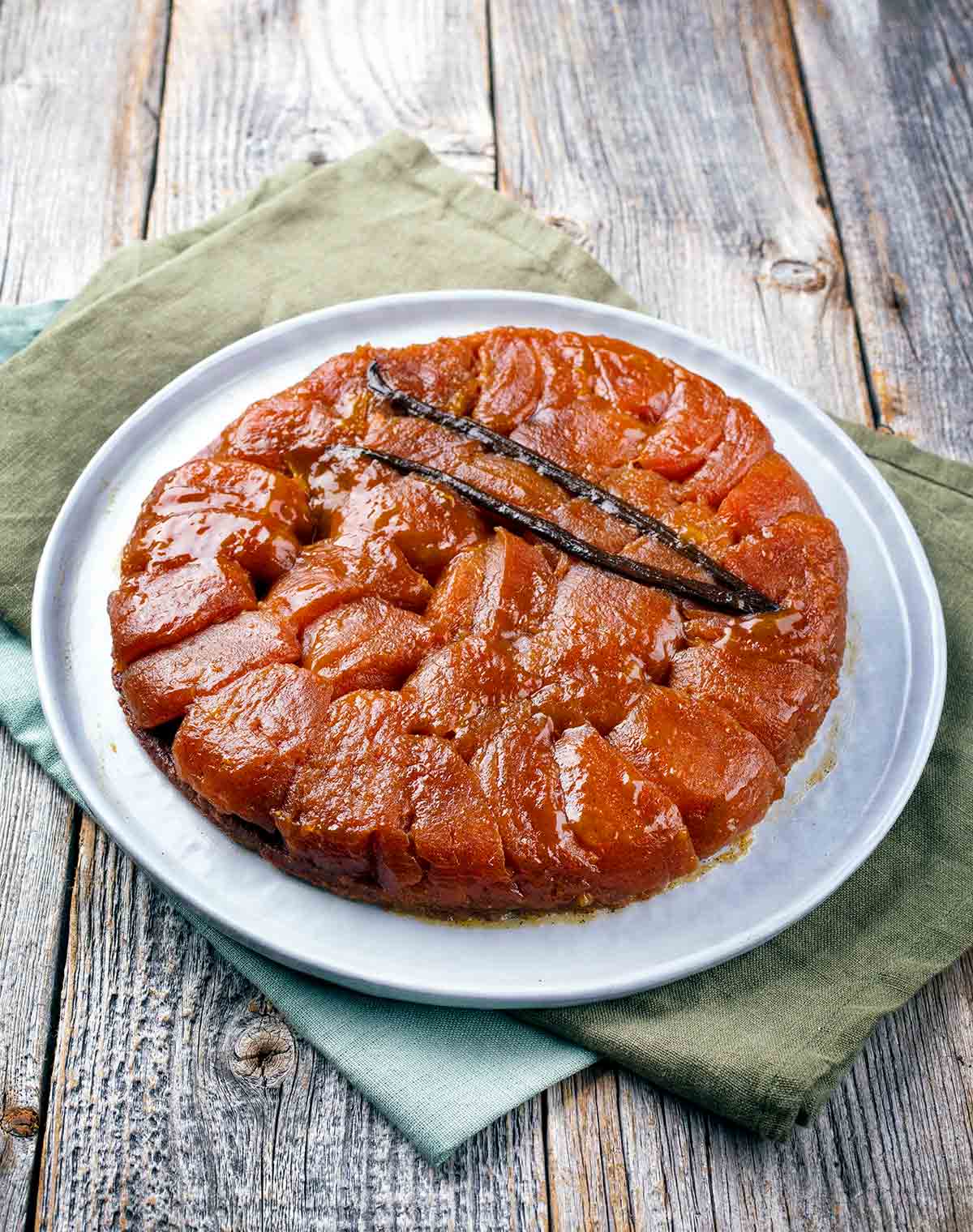 A tarte tatin on a white plate on a wooden table.