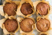 A muffin tin filled with pumpkin muffins in paper liners.