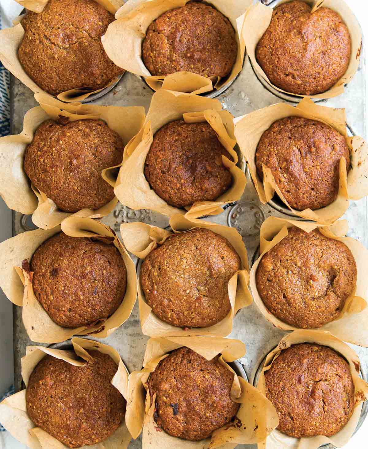 A muffin tin filled with pumpkin muffins in paper liners.
