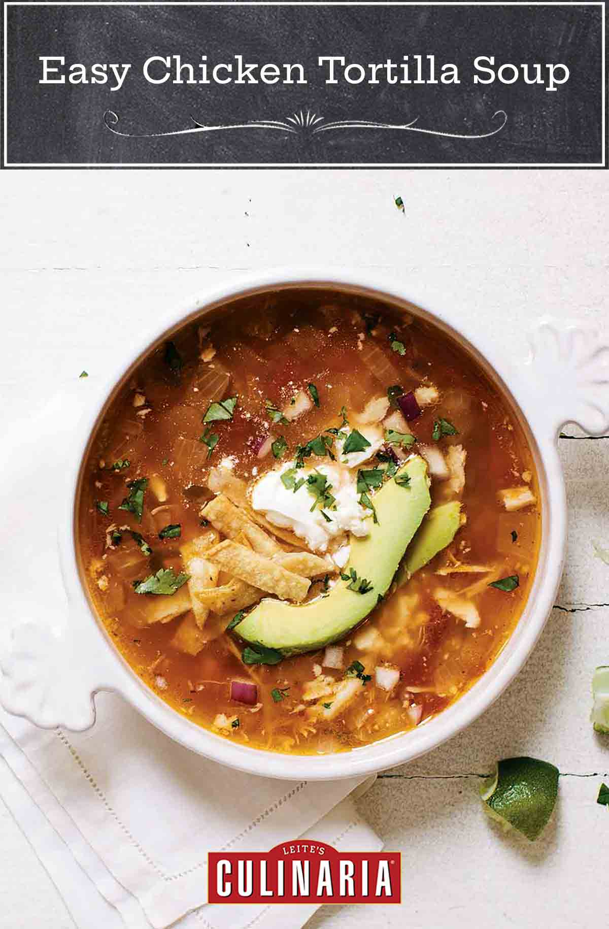 A bowl of easy chicken tortilla soup, with chicken, avocado, tortilla strips, and sour cream.