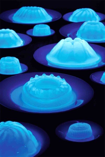 Several plates with fluorescent glowing Jello molds.