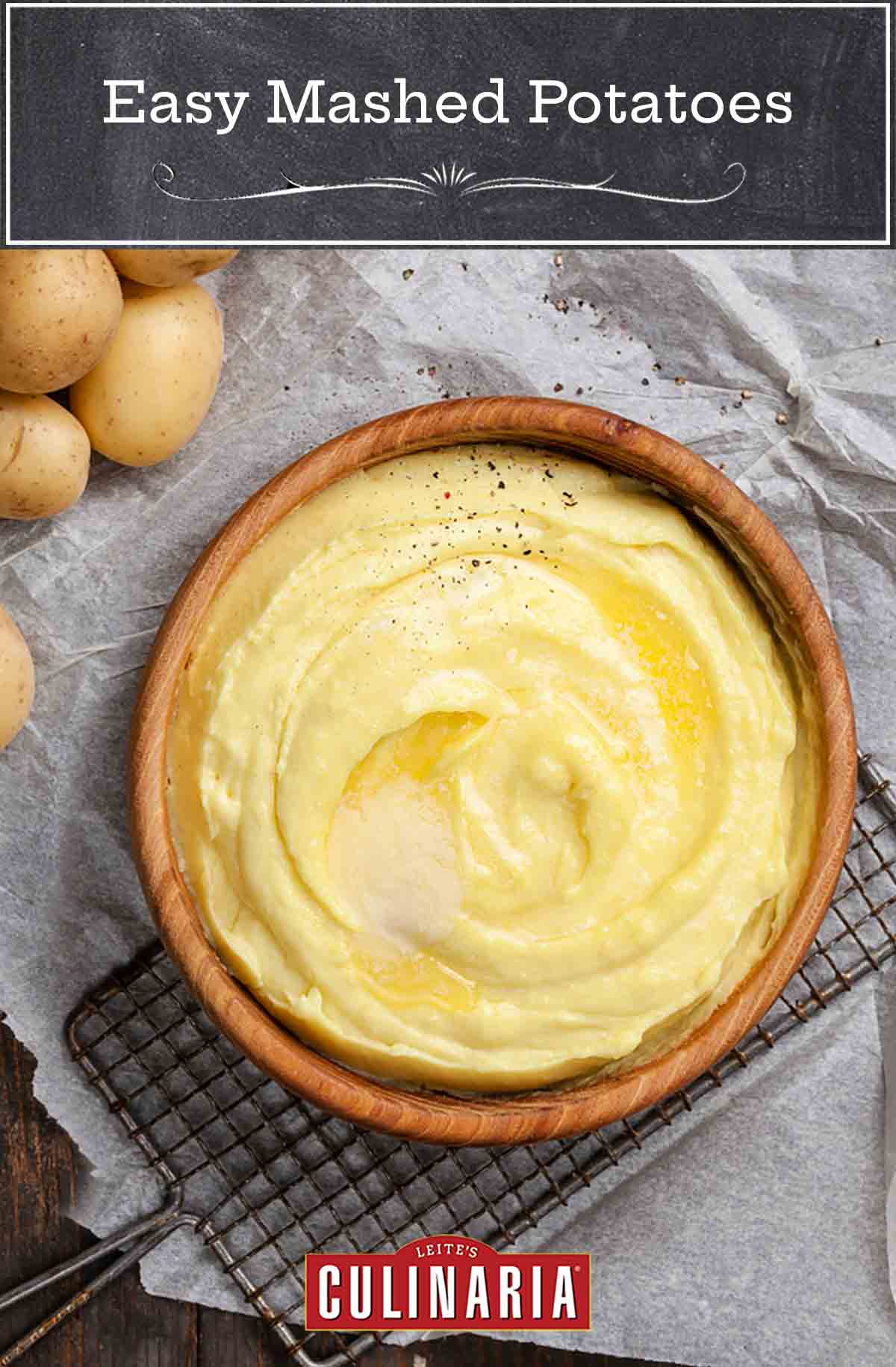 A wooden bowl filled with mashed potatoes and topped with a melted square of butter.