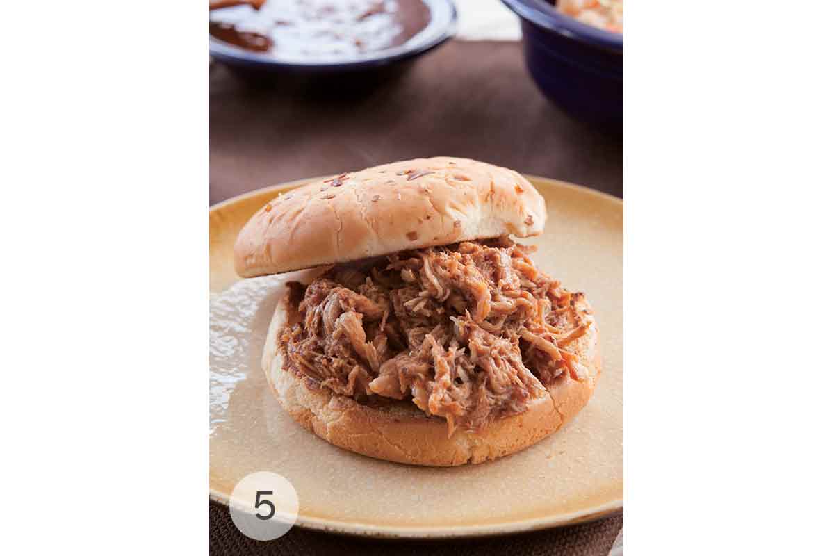 Slow cooker pulled pork piled on a bun on a plate.