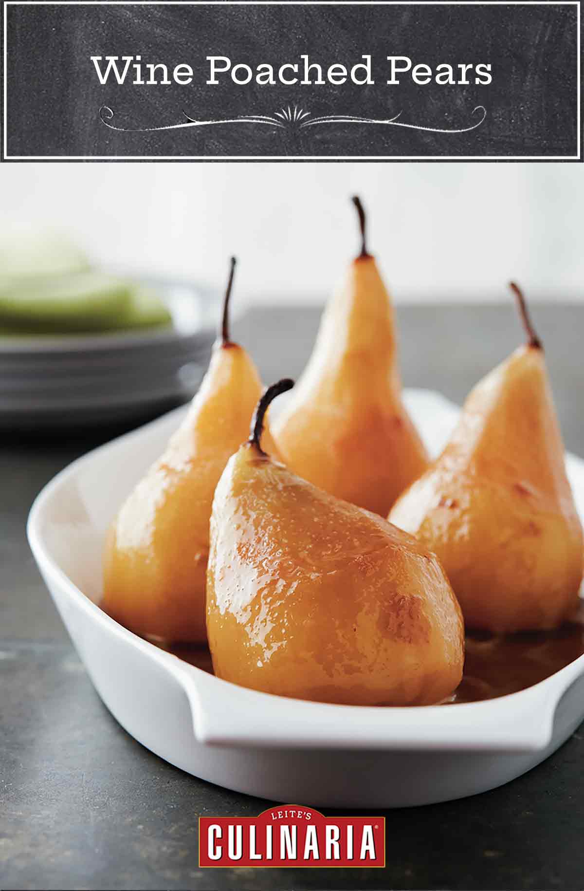 Four wine poached pears in a shallow white baking dish.