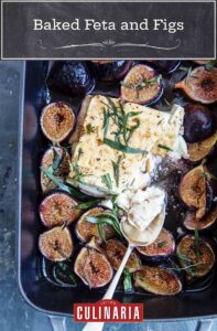 A rectangular baking dish with a block of cooked feta in the center, surrounded by halved figs and tarragon leaves.