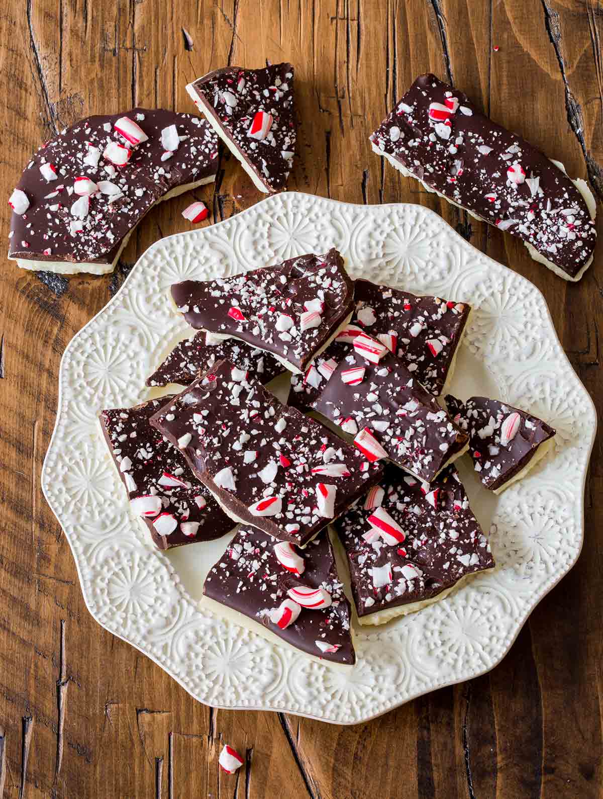 A decorative white plate filled with irregular pieces of candy cane bark.