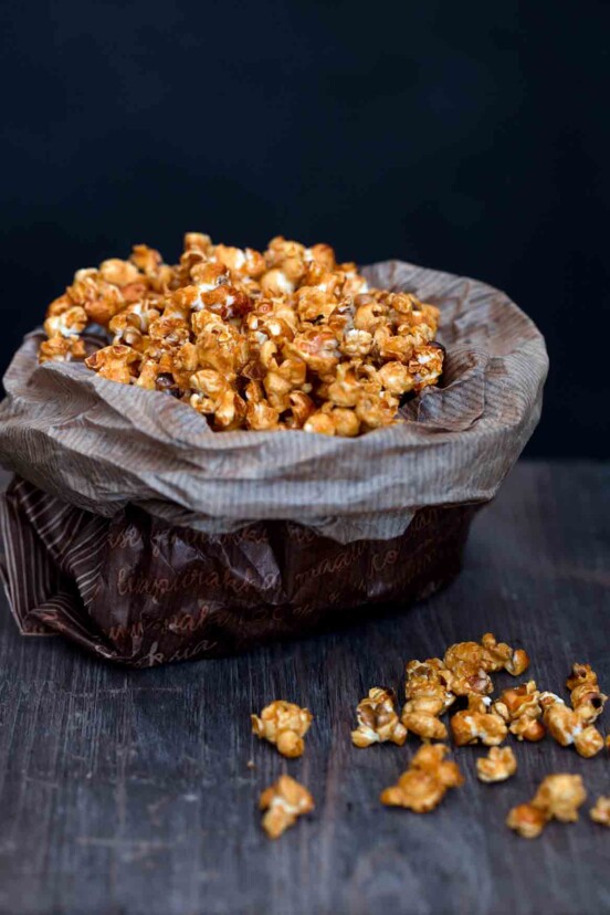 A waxed paper bag filled with caramel popcorn.