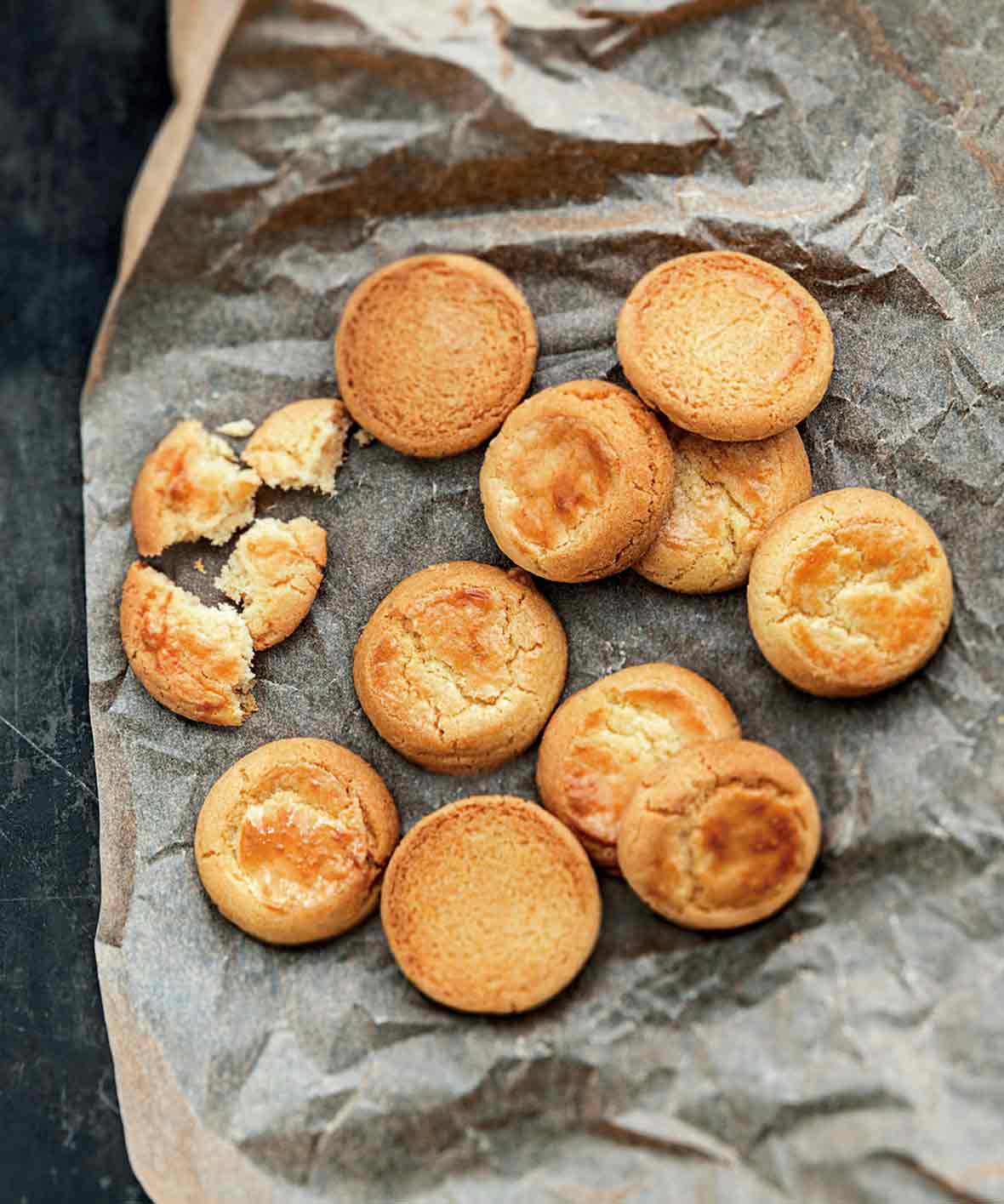 Ten whole, plus one broken butter cookies on a piece of crumpled parchment paper.