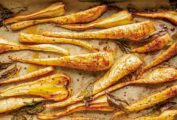 Sheet pan lined with parchment and sliced maple roasted parsnips.