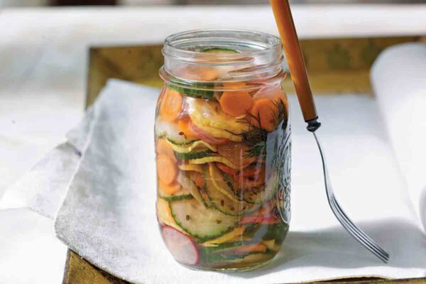 A jar of refrigerator pickles on a white napkin with a fork resting against the jar.