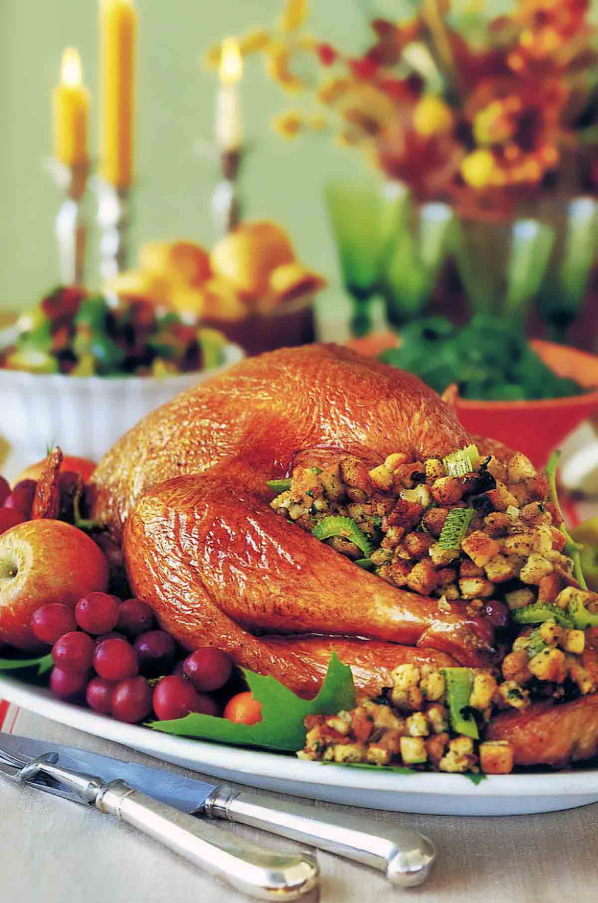 Thanksgiving table with a roast turkey with stuffing and vegetables on a platter.