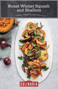 A white oval platter topped with roast winter squash and shallots.
