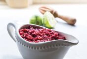 A white gravy boat filled with cranberry relish with a halved lime and juicer in the background.