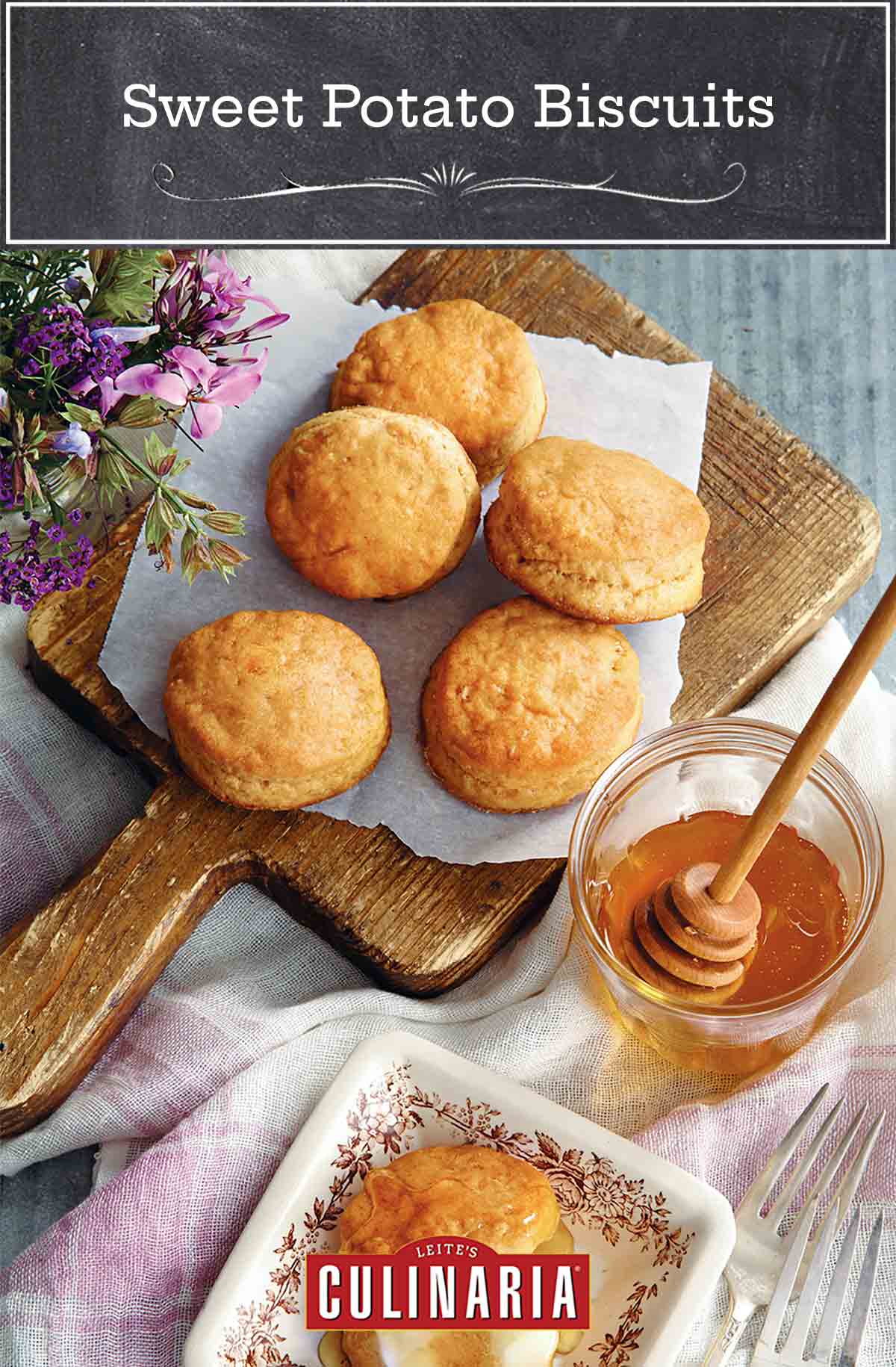 A cutting board with five sweet potato biscuits on it and a square plate square with a split biscuits spread with butter and honey.