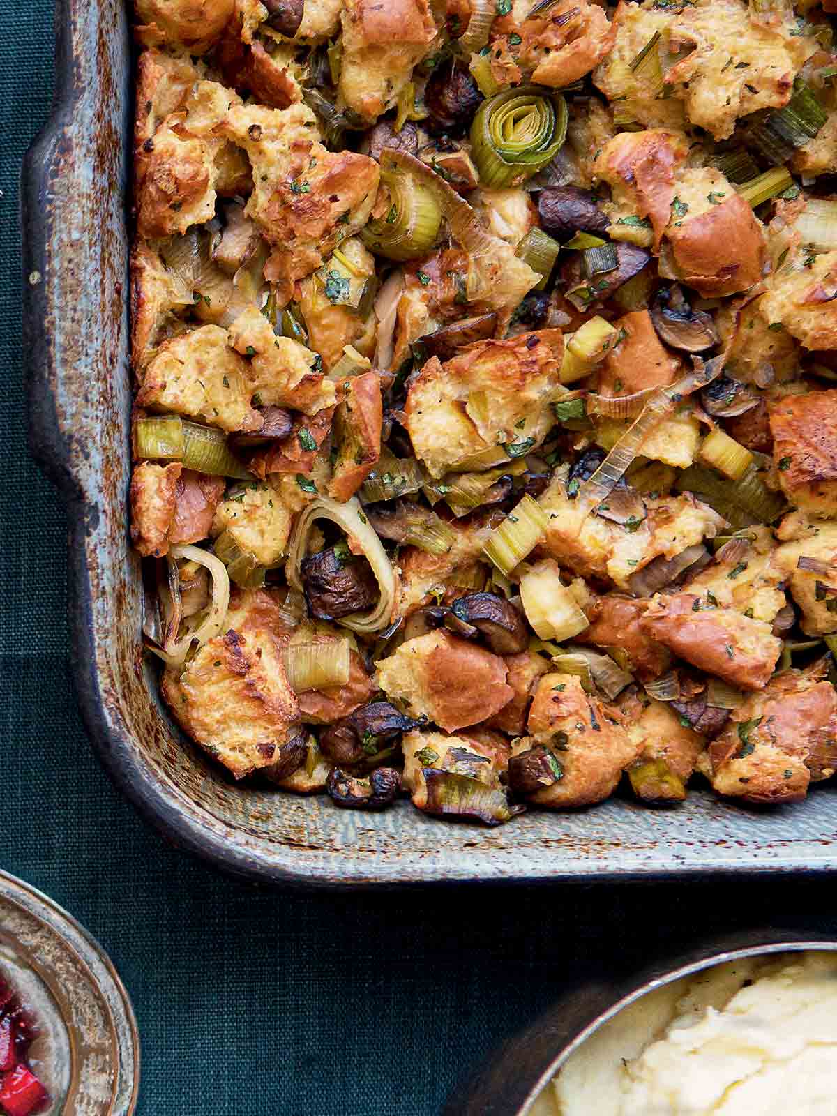 A rectangular baking dish filled with wild mushroom stuffing with leeks.