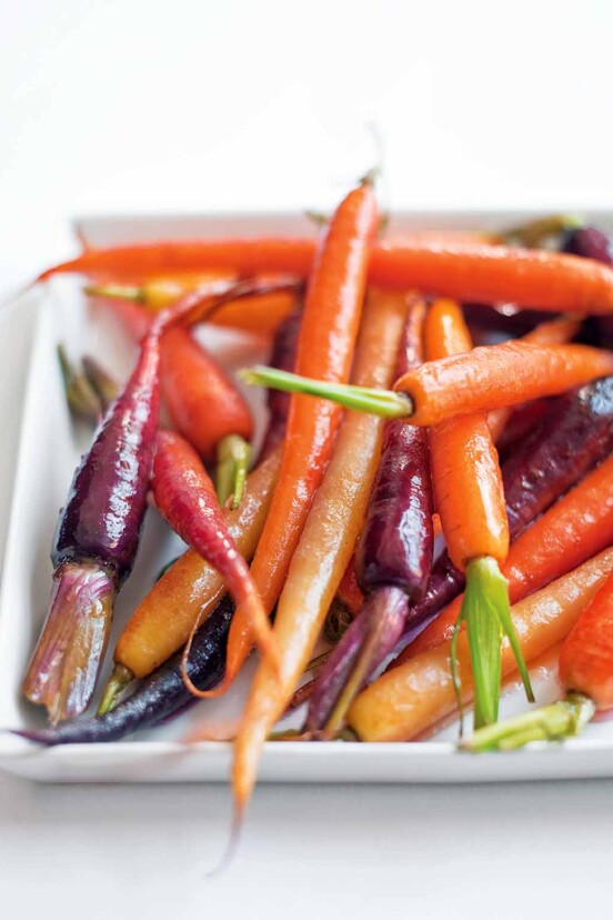 White plate filled with orange, purple, and yellow candied carrots.