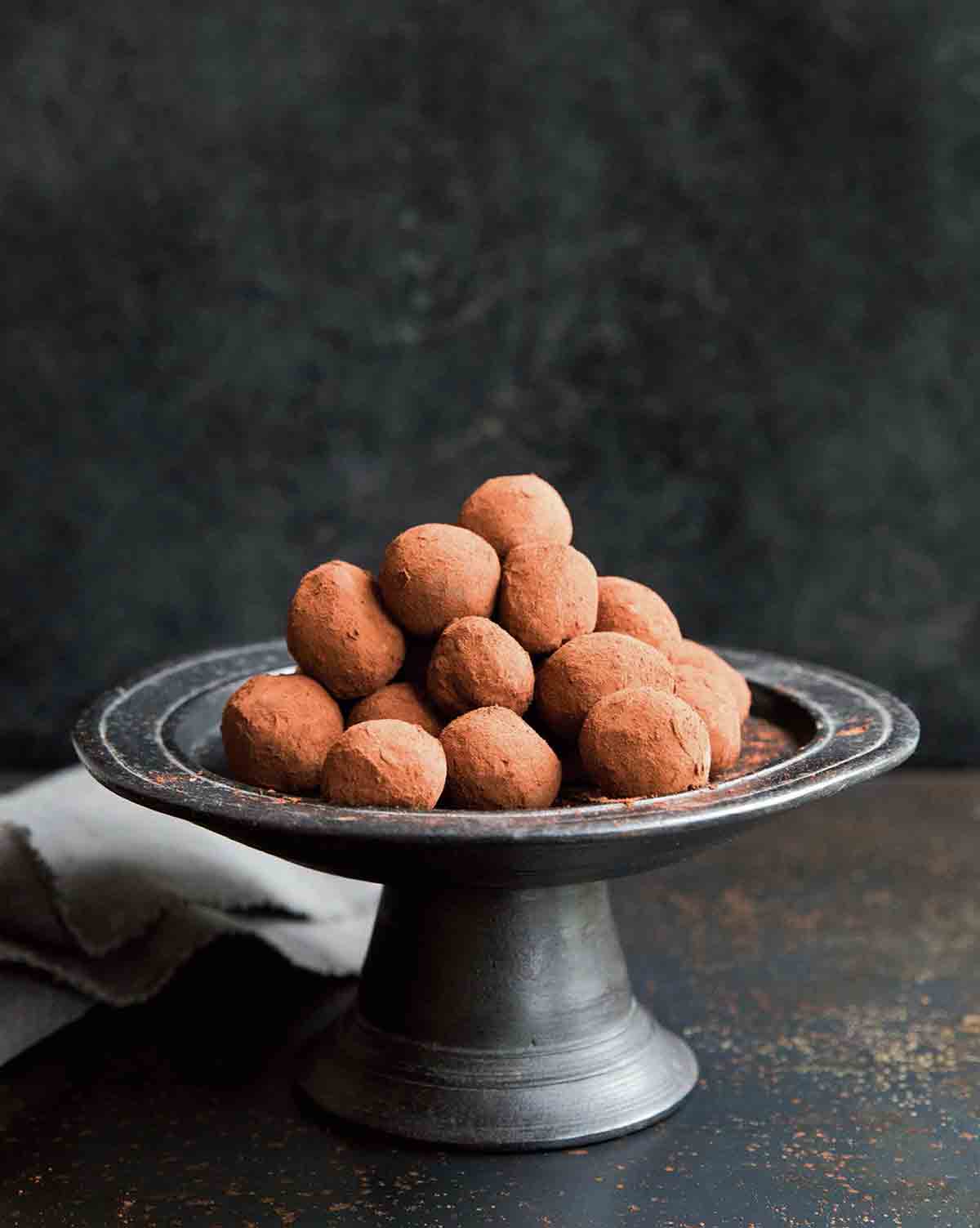 A pewter cake stand piled with chocolate truffles.